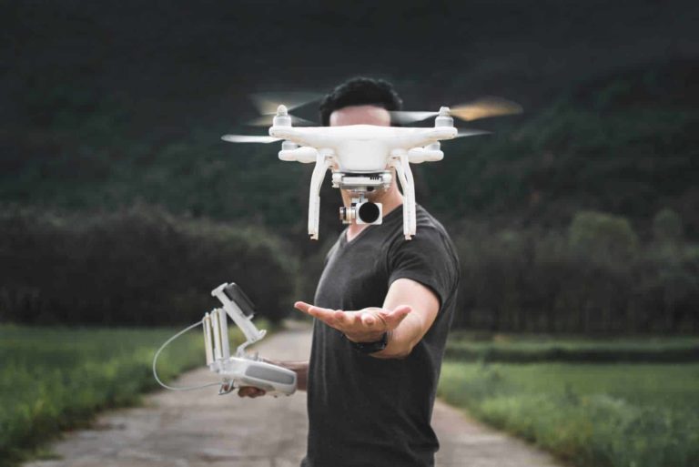 Pricing your used and second hand drones, man controlling small white drone, holding controller.